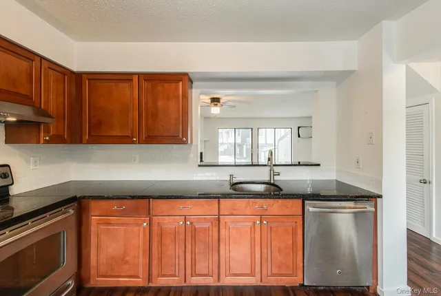 a kitchen with granite countertop stainless steel appliances a sink window and cabinets