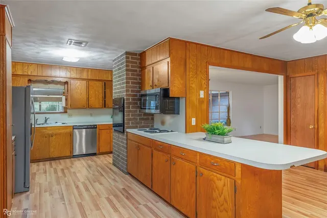 a kitchen with stainless steel appliances granite countertop wooden cabinets a oven and a sink