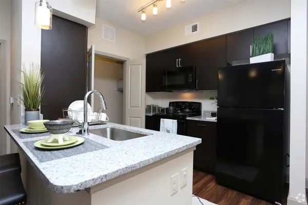 a kitchen with granite countertop a stove a sink and a refrigerator