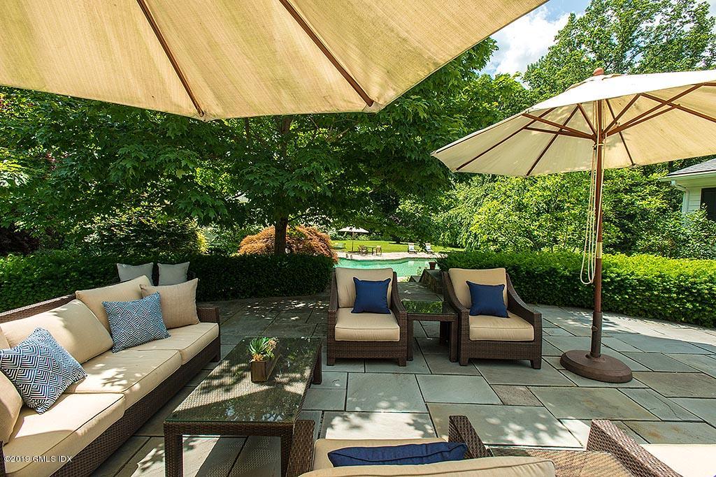62 Sumner Road Greenwich, CT 06831 - Photo 18 of 25 a view of a patio with couches chairs under an umbrella