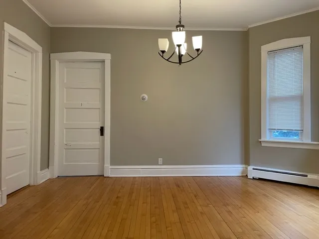 an empty room with wooden floor cabinet and windows