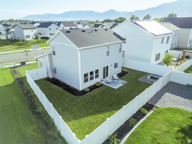 1486 West 2055th Street South Logan, UT 84339 - Photo 38 of 45 Expansive backyard featuring a manicured lawn, a large concrete patio, and a dedicated fire pit area