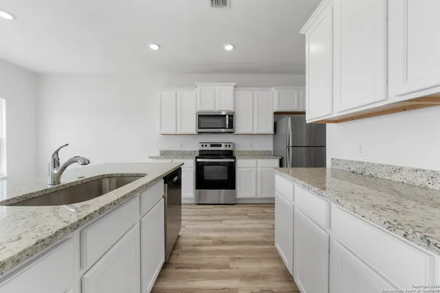 a kitchen with granite countertop white cabinets and stainless steel appliances