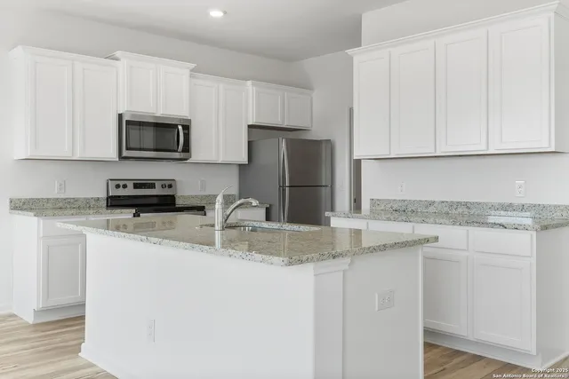 a kitchen with granite countertop a sink a stove a microwave and cabinets