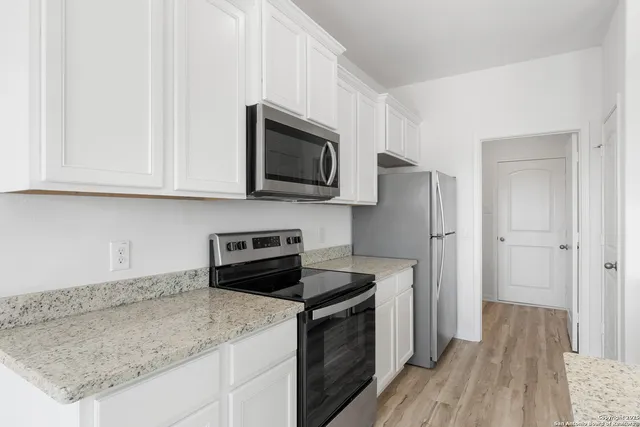 a kitchen with stainless steel appliances granite countertop a stove a microwave and a white cabinets