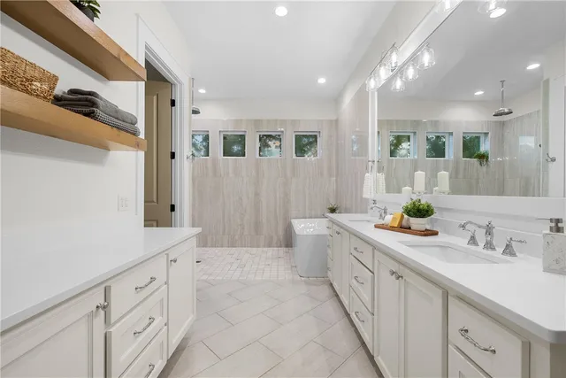 a spacious bathroom with a double vanity sink a mirror and a bathtub