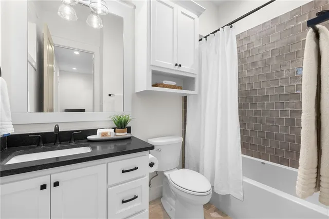 a bathroom with a granite countertop sink a toilet and shower