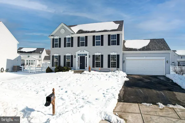 a front view of a house with a yard covered in snow