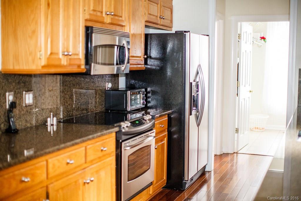 12521 Hawks Ridge Road Huntersville, NC 28078 - Photo 3 of 24 a kitchen with stainless steel appliances granite countertop a refrigerator a stove and a sink with wooden floor