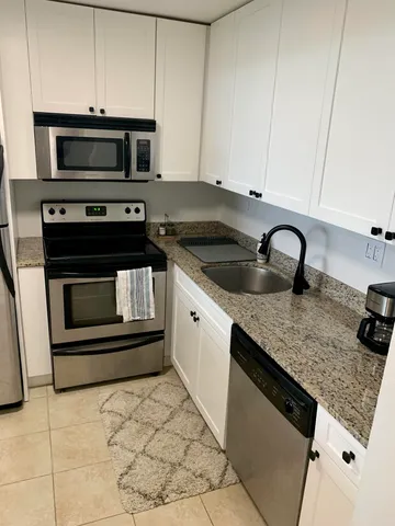 a kitchen with granite countertop a refrigerator sink stove and oven