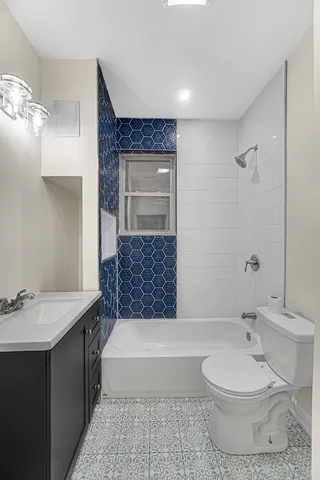 a bathroom with a granite countertop bathtub sink vanity mirror and toilet