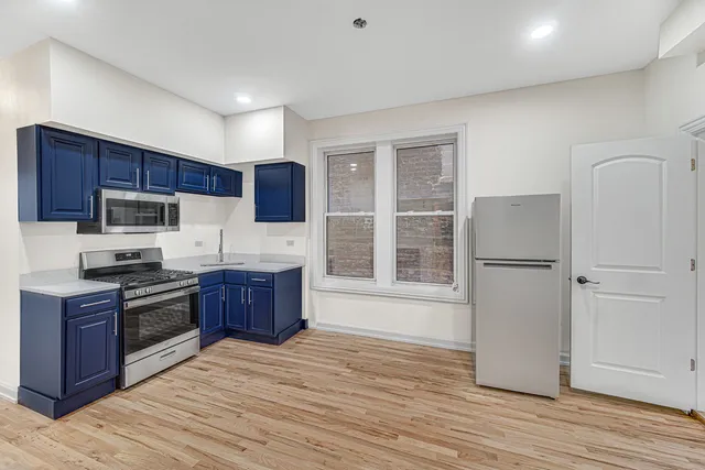 a kitchen with stainless steel appliances granite countertop a stove a sink dishwasher a refrigerator and a microwave oven with wooden floor