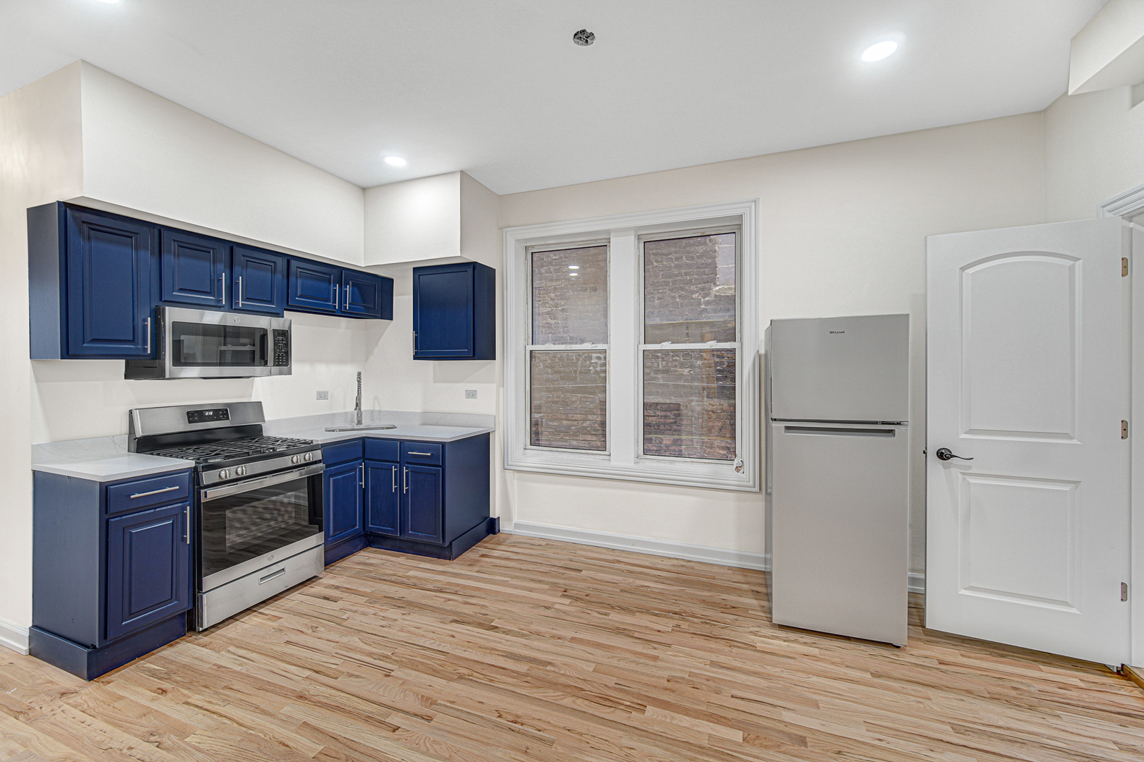 2623 West 21st Place Chicago, IL 60608 - Photo 8 of 29 a kitchen with stainless steel appliances granite countertop a stove a sink dishwasher a refrigerator and a microwave oven with wooden floor