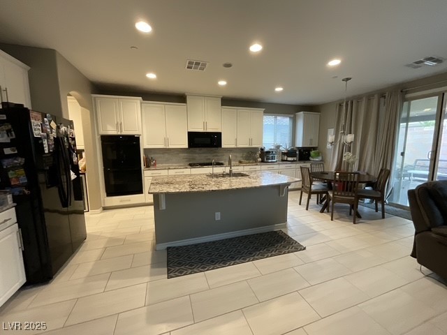 Undisclosed Address Henderson, NV 89011 - Photo 2 of 30 Kitchen featuring clean white cabinets black appliances, tasteful backsplash, light stone counters, spacious breakfast nook area to family spaces open and and airy, and recessed lighting