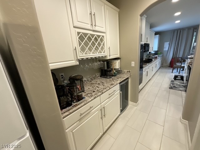 Undisclosed Address Henderson, NV 89011 - Photo 3 of 30 Easy accessible connecting from living room to kitchen featuring beverage and coffee bar and spacious pantry nest to it walkways, white cabinets, light tile patterned floors, light stone counters, and wine cooler