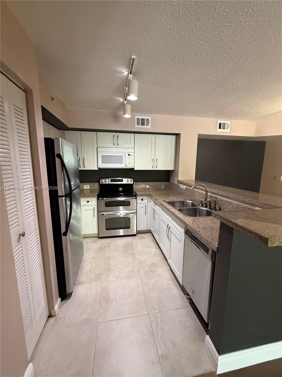 2113 Renaissance Boulevard, Unit 203 Miramar, FL 33025 - Photo 4 of 19 a large white kitchen with stainless steel appliances granite countertop a stove refrigerator and a sink