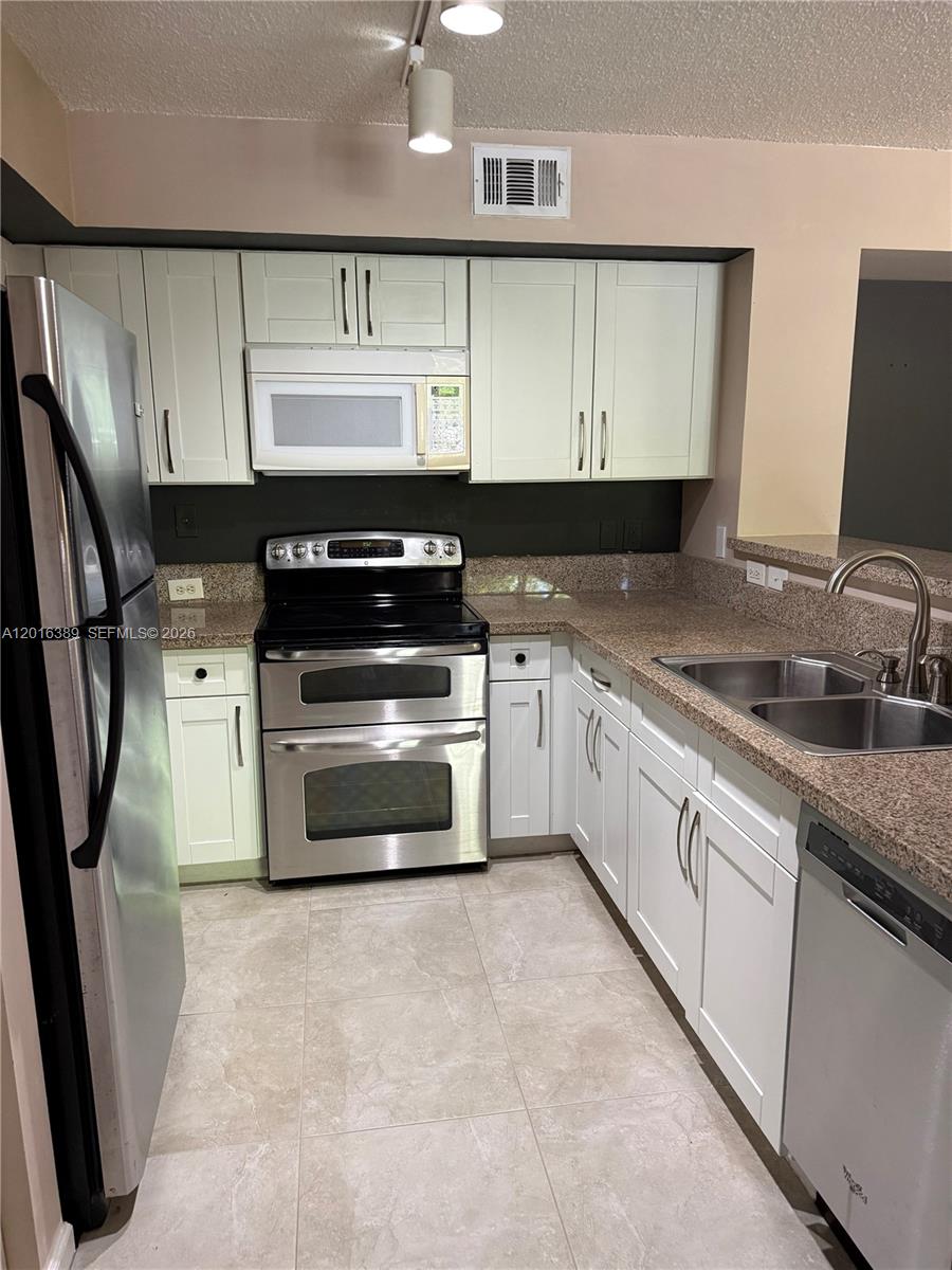2113 Renaissance Boulevard, Unit 203 Miramar, FL 33025 - Photo 5 of 19 a kitchen with stainless steel appliances a sink dishwasher stove and cabinets