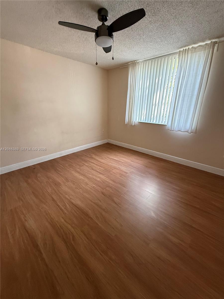 2113 Renaissance Boulevard, Unit 203 Miramar, FL 33025 - Photo 10 of 19 an empty room with wooden floor fan and windows