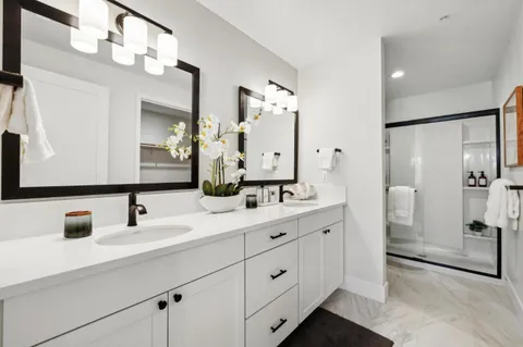 a bathroom with a double vanity sink mirror and shower