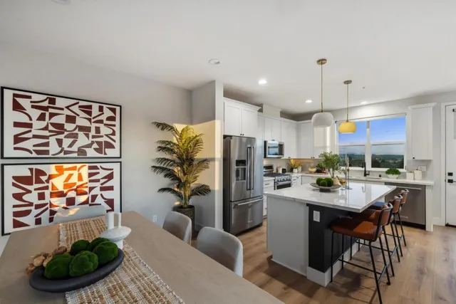 a kitchen with stainless steel appliances kitchen island granite countertop a refrigerator a stove a microwave oven a sink with a dining table and chairs