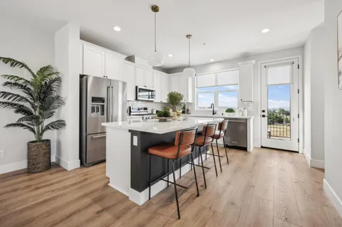 a kitchen with stainless steel appliances a dining table chairs stove refrigerator and cabinets