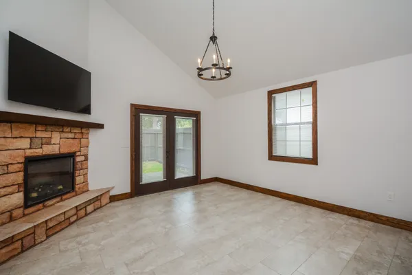 a view of an empty room with flat screen tv a fireplace and a window