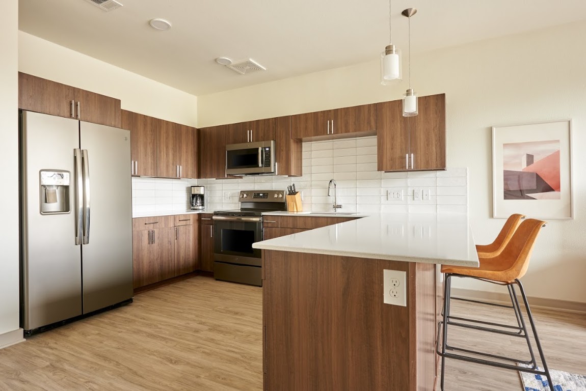 4811 Woodrow Avenue, Unit 219 Austin, TX 78756 - Photo 3 of 4 a kitchen with stainless steel appliances wooden floor and a refrigerator