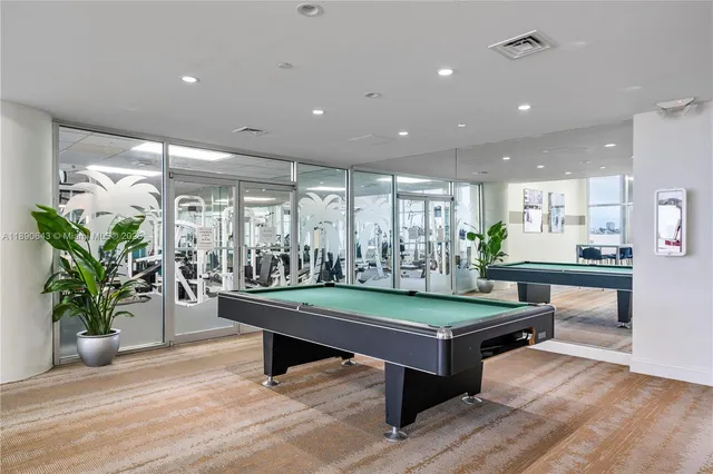 a room with wooden floor pool table and windows