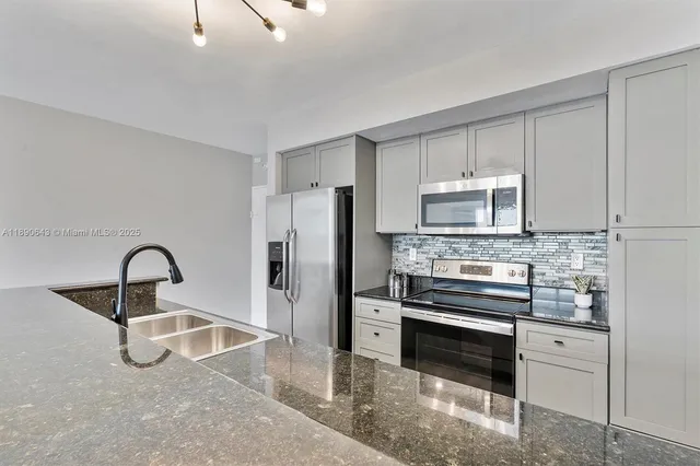 a kitchen with stainless steel appliances kitchen island a refrigerator sink and cabinets