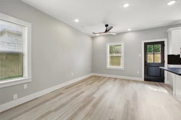 a view of an empty room with a window and wooden floor