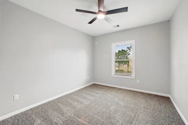 an empty room with a window and a fan