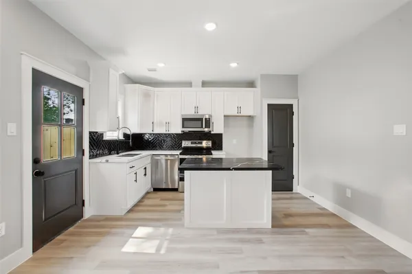 a kitchen with granite countertop a refrigerator stove top oven and sink