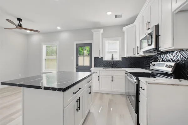 a kitchen with granite countertop a sink a stove and cabinets