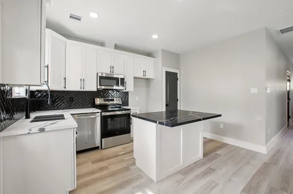 a kitchen with granite countertop white cabinets and white appliances