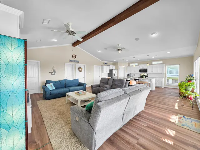 a living room with furniture kitchen view and a wooden floor
