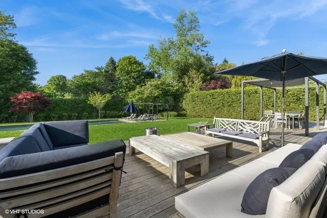 a view of a patio with couches table and chairs under an umbrella with a barbeque