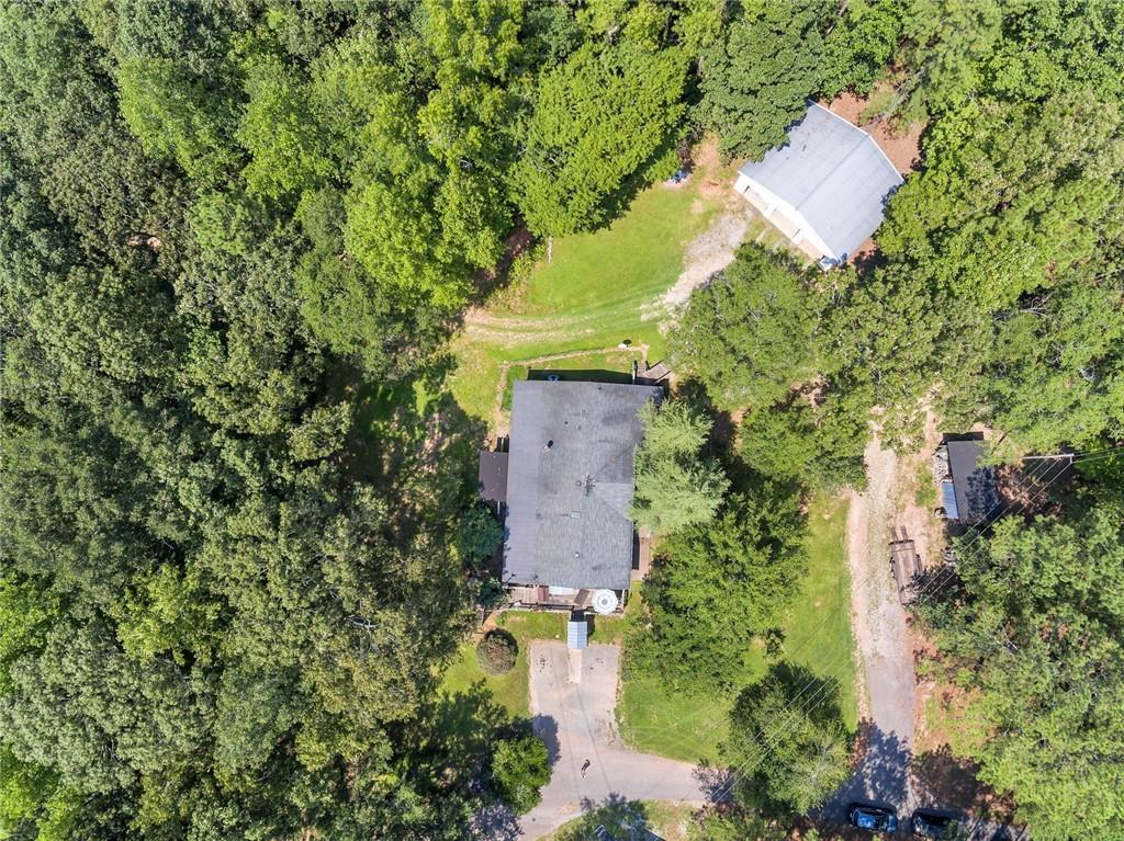 an aerial view of a house with outdoor space and trees all around