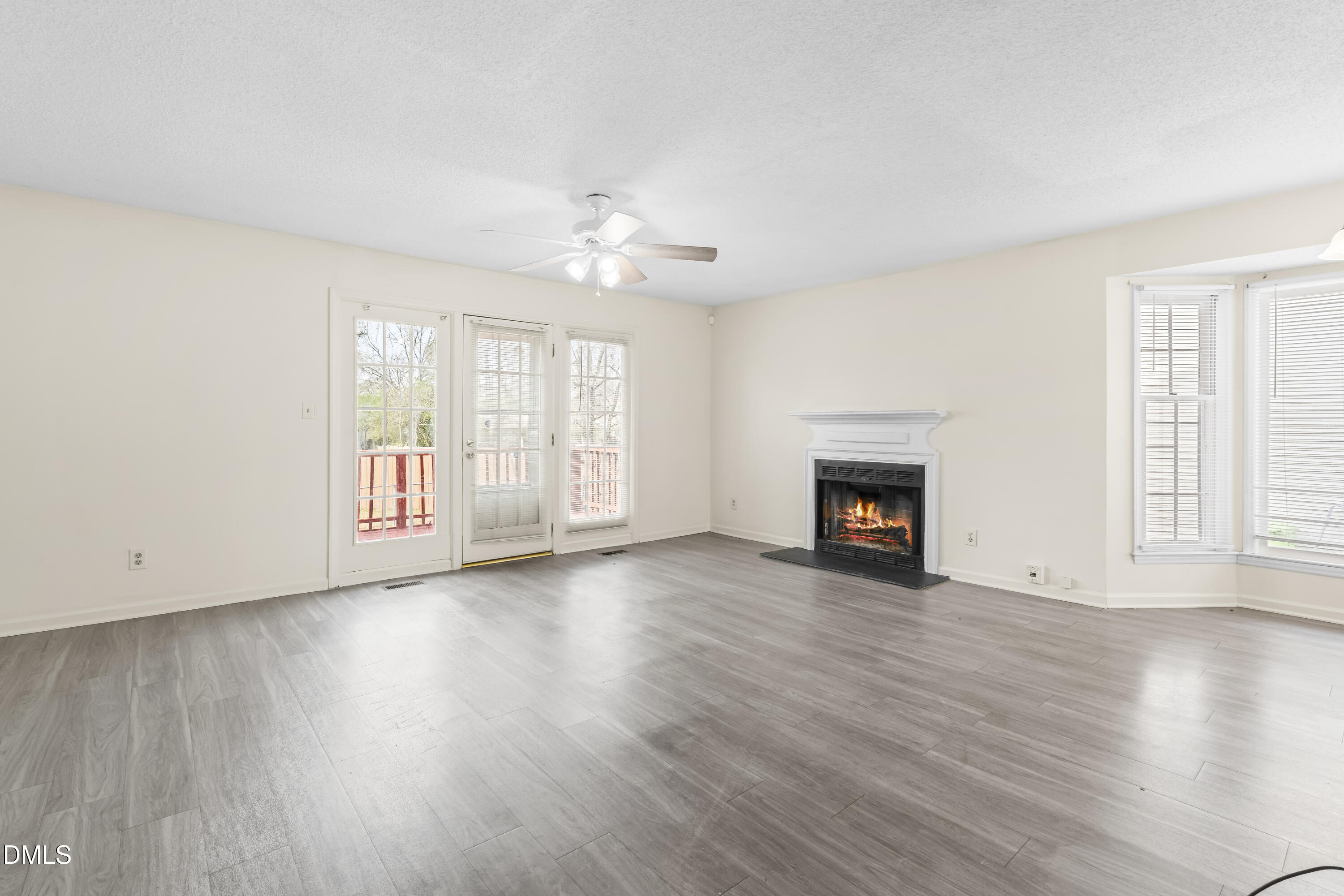 8031 Perry Creek Road Raleigh, NC 27616 - Photo 11 of 28 an empty room with wooden floor fireplace and windows