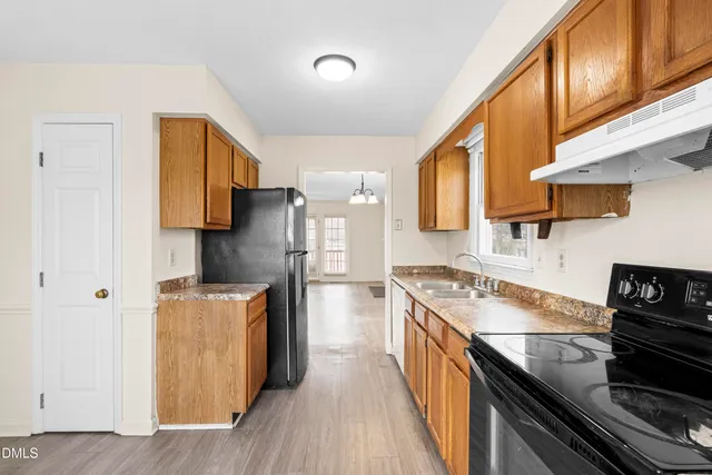 a kitchen with stainless steel appliances granite countertop a stove a refrigerator a sink dishwasher and wooden cabinets with wooden floor