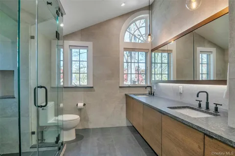 a bathroom with a sink a toilet a mirror and window