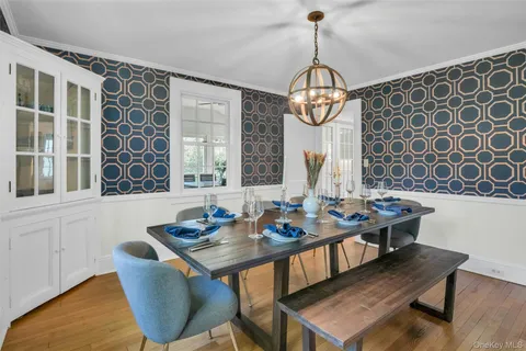 a dining room with wooden floor a chandelier a wooden table and chairs