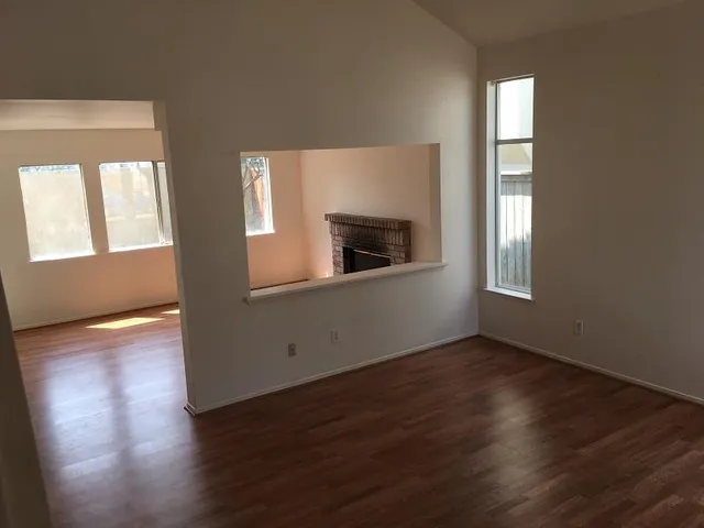 an empty room with wooden floor cabinet and windows