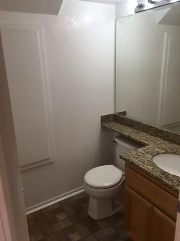 a bathroom with a granite countertop toilet and a sink