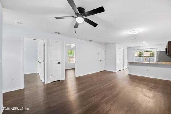 an empty room with wooden floor and fan