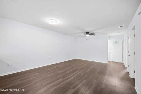 an empty room with wooden floor and windows