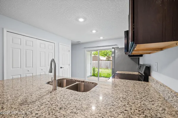 a kitchen with stainless steel appliances granite countertop a refrigerator a stove a sink and a microwave