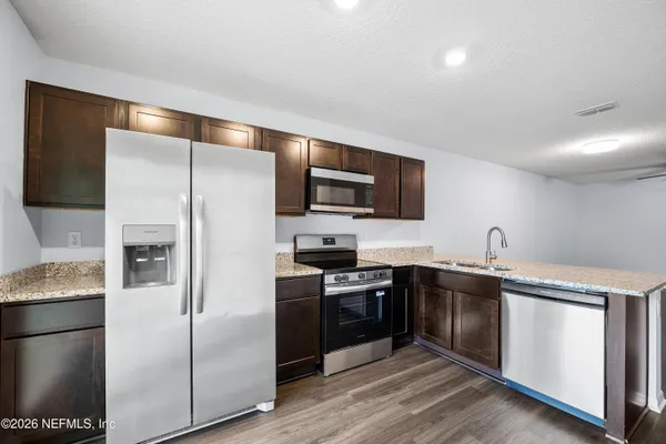 a kitchen with stainless steel appliances granite countertop a refrigerator a stove a sink and a microwave