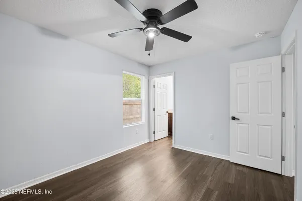 an empty room with wooden floor ceiling fan and windows