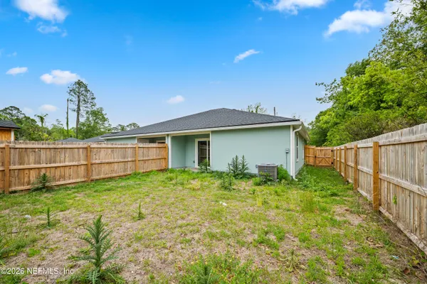 a view of a backyard with plants and large trees