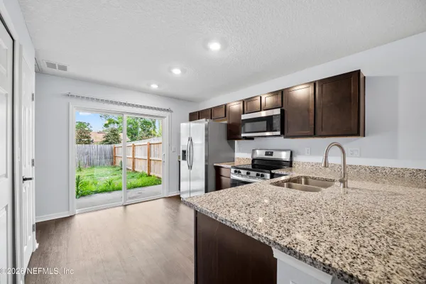 a kitchen with kitchen island granite countertop a sink and a stove top oven with wooden floor
